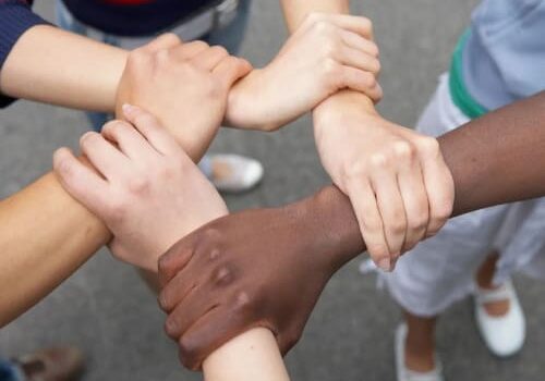 A group of people holding hands in the middle of a circle.