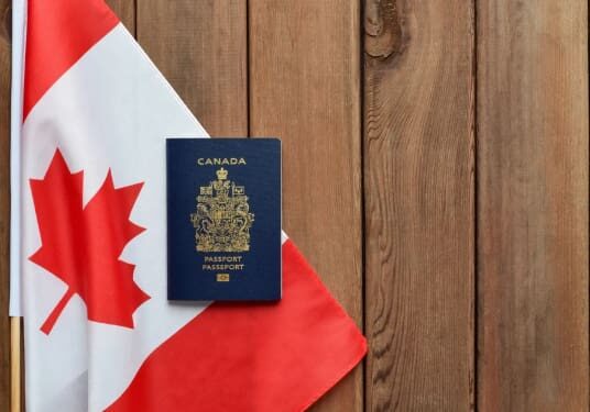 A canadian passport sitting on top of an american flag.